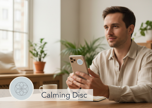 Man using a smartphone with a 'Calming Disc' sticker in a home setting
